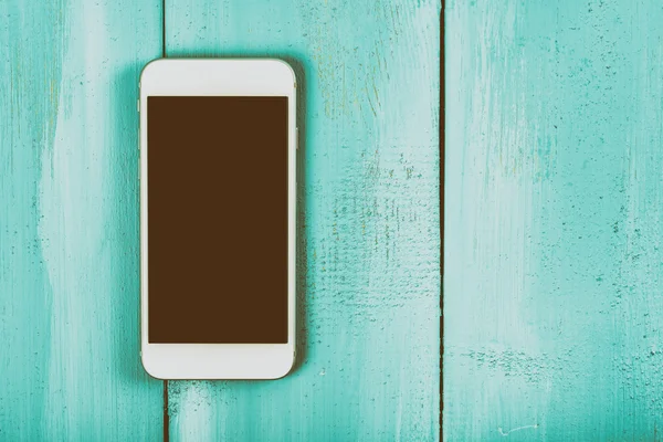 Белый мобильный телефон с пустым экраном на деревянном столе — стоковое фото
