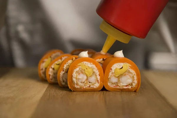 Suşi ustası Japonlara servis yapıyor. Tahta tahtada mayonezli pirinç rulosu yok. Şef tempura karidesli yemek hazırlıyor. Sushi Roll servis ediliyor. Profesyonel aşçılık süreci. natürmort 