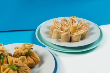 Geleneksel Rus kreplerinin iki çeşidine yakın. Et ve somon balıklı Blini. Noel tatili yemekleri. Yeni yıl servisi. Mavi soyut arka planda servis edilen ince Rus krepleri.