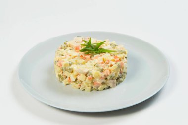 Geleneksel Rus Olivier salatasını yakın plan. Mayonez soslu haşlanmış sebze tabağı. Yılbaşı soğuk yemeği gri tabakta servis edilir. Nesne arka planda izole edildi.