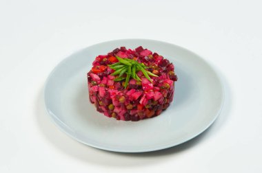 Rus sirkeli pancar salatasının yan görüntüsü. Beyaz zemin üzerinde taze soğan soğanları ve yağ ve sirke ile servis edilen geleneksel salata. Haşlanmış sebze salatası.