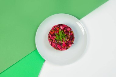 Rus sirkeli sebze pancar salatasının tam üstünde. Renkli yeşil arka planda taze soğan soğanları ile servis edilen yağ ve sirkeli geleneksel salata.