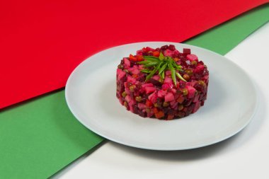 Rus sirke salatası ve pancar salatası. Yağ ve sirkeli geleneksel salata. Renkli yeşil ve kırmızı arka planda taze soğan soğanı ile servis ediliyor..
