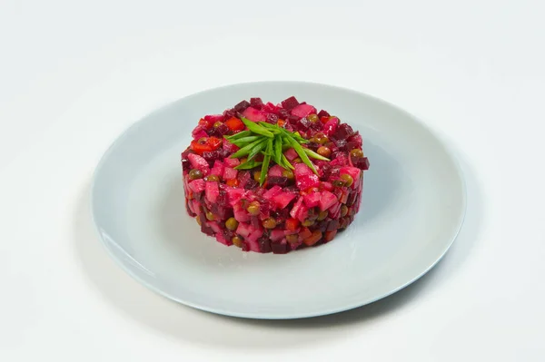 Rus sirkeli pancar salatasının yan görüntüsü. Beyaz zemin üzerinde taze soğan soğanları ve yağ ve sirke ile servis edilen geleneksel salata. Haşlanmış sebze salatası.
