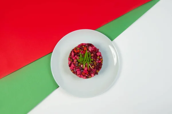 Rus sirkeli sebze salatası pancar salatasının en üst görüntüsü. Yağ ve sirkeli geleneksel salata. Renkli yeşil ve kırmızı arka planda taze soğan soğanı ile servis ediliyor..