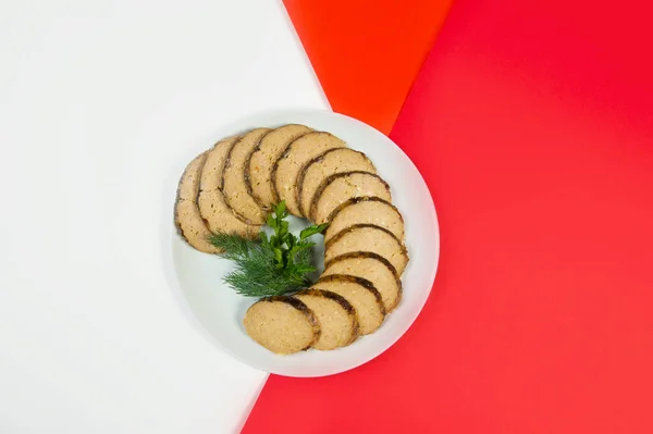 Stuffed carp fish. Jewish traditional gefilte fish slices served with fresh green herbs - dill and parsley on red and white abstract background. Holiday dish of minced fish and vegetables — Stock Image Stuffed Carp Fish Jewish Traditional Gefilte Fish Slices Served Fresh Stock Picture