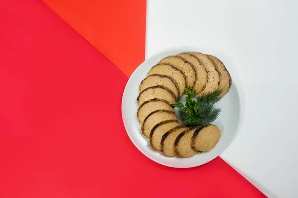 Stuffed carp fish. Jewish traditional gefilte fish slices served with fresh green herbs - dill and parsley on red and white abstract background. Holiday homemade dish — Stock Image Stuffed Carp Fish Jewish Traditional Gefilte Fish Slices Served Fresh Stock Image