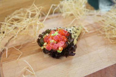 Japon Temaki Suşi Salatası 'na yakın, Maguro ton balığı, avokado, uçan balık yumurtası Tobiko (Masago), marul yaprağı, pirinç ve Mamenori yosunuyla kaplı ahşap tahta üzerinde dekoratif samanla servis edilir.