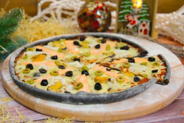 Tahtada servis edilen İtalyan siyah hamurlu pizzayı kapat ve arka planda yılbaşı süsü olsun. Kırmızı balık fileto, yeşil ve siyah zeytin, midye, kalamar.