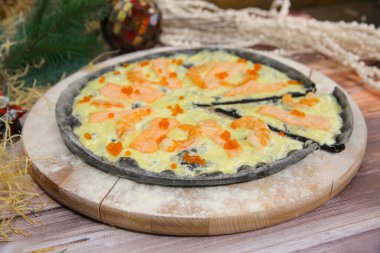 Ahşap tabakta servis edilen İtalyan siyah hamurlu pizzayı ve arka planda yılbaşı süslemesi olan masayı kapat. Kırmızı balık dilimli deniz ürünleri yemeği, siyah kaplan karidesi ve kırmızı havyar.