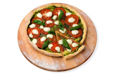 Caprese salata stili İtalyan pizzası dilimlenmiş domates, mozzarella peyniri ahşap tabakta taze fesleğen yaprağı ve baharatla servis edilen pesto sosu. 