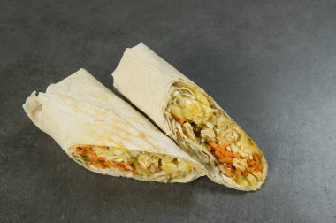 Koyu taştan arka planda servis edilen tavuk etli shawarma. Havuçlu jiroskoplar, peynir, salatalık turşusu lahana ve lahanalı patates kızartması. Izgara tzatziki.