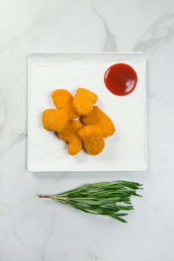 Beyaz mermer arka planda domates ketçap sosuyla servis edilen altı tavuk parçasının hemen üstünde. Kare tabağın yanında taze yeşil biberiye brunch 'ı. Minimalist yemek menüsü konsepti