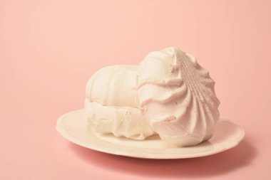 Şekerleme ve kremaya benzer şekilde organik pektin ve yumurta beyazından yapılmış sufle kabuklu tatlı zefiri (zephyr) parçaları. Pastel kayısı arka planında beyaz tabakta servis edilmiş. Boşluk resmini kopyala