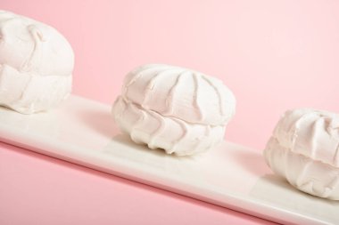 Geleneksel Rus zefiri (zephyr), beyaz tabakta servis edilen krema ve kremaya benzer şekilde, pastel pembe arka plan. Organik pekten yapılmış tatlı, yumurta beyazı. Seçici odak