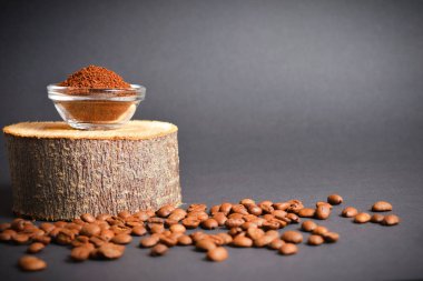 Ahşap kütükte cam kasede servis edilen kavrulmuş öğütülmüş kahve, koyu arkaplanda dağınık kahve çekirdekleri. Yüksek kaliteli organik aroma tohumları. Boşluk metin resmini kopyala