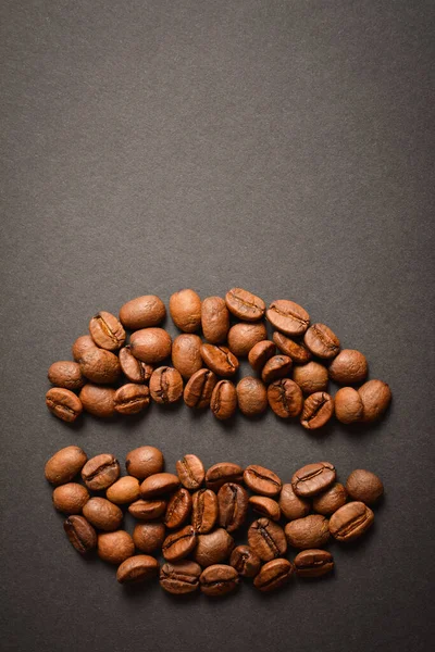 Vertical image of Coffee bean shape isolated on dark background. Coffee seed silhouette of roasted high quality coffee beans. Aroma drink