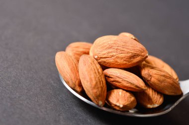 Gümüş metal paslanmaz çelik kaşıkta servis edilen Macro fındık. Karanlık arka planda badem. Yaratıcı gıda konsepti. Çiğ fındık. Uzay resmini kopyala. Tek bir nesne. Mutfak hala hayat dolu