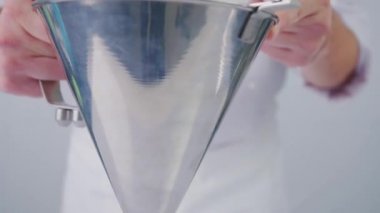 Pasta şefi tatlı yapıyor. Kırmızı böğürtlen sosu yavaş çekimde beyaz arka plana dökülüyor. Kırmızı sos beyaz bir masaya dökülüyor..