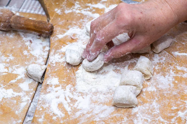 A woman makes dumplings with her hands on a wooden cutting Board — Stock Photo, Image