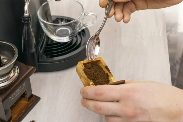a person makes coffee in a coffee machine picks up ground coffee with a spoon from a coffee grinder drawer. High quality photo