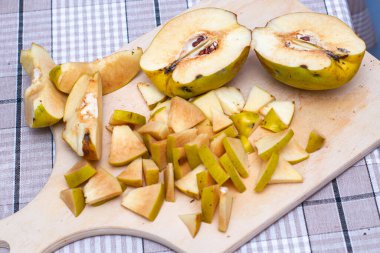 Ayva, reçel yapmak için dilimlenmiş, tahta kesme tahtasının üzerinde yatıyor.