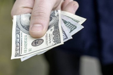 El, yarım yamalak birkaç yüz dolarlık banknot tutuyor.