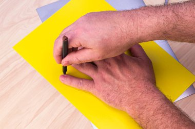 Bir Paskalya tavşanını kendi ellerinle yapma kavramını bir insan sarı bir kağıt parçasındaki kalemle avucunun içine alır. Yüksek kalite fotoğraf