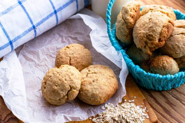 Ev yapımı yulaf ezmesi kurabiyeleri bir avuç yulaf lapası ve kesme tahtasının üzerinde pişen kağıt üzerinde yatar.