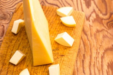 Tahta bir tahtanın üzerinde küçük parçalarla çevrili büyük bir peynir parçası. Yüksek kalite fotoğraf