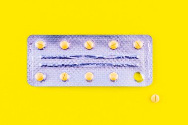 Sarı arka planda tabletleri olan su toplayan bir tablet çıkartılır ve yanında yatar. Yüksek kalite fotoğraf