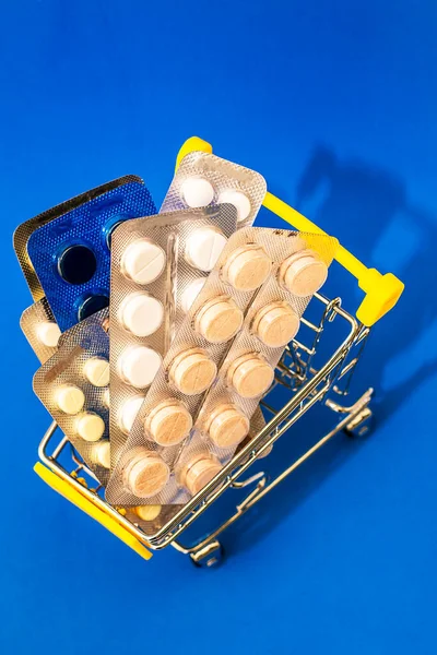 blisters with pills in a grocery cart on a blue background. High quality photo