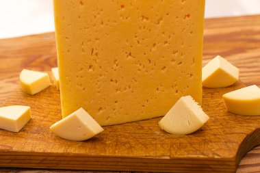 Tahta bir tahtanın üzerinde küçük parçalarla çevrili büyük bir peynir parçası. Yüksek kalite fotoğraf