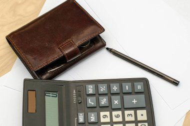 Hesap makinesi cüzdanı ve dolmakalem beyaz kağıt tabakalarının üzerinde.