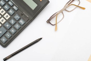 Hesap makinesi gözlüğü ve dolmakalem beyaz bir kağıt üzerinde. Yüksek kalite fotoğraf