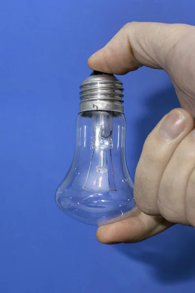incandescent lamp in the hand of a person on a blue background. High quality photo