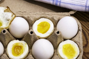Masadaki karton bir kutunun içindeki yumurtalar bazı yumurtalar bütündür diğerleri farklı derecelerde hazırlıklıdır. Yüksek kalite fotoğraf