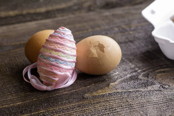 eggs on a wooden table with an egg decorated with an Easter ribbon another egg is split. High quality photo