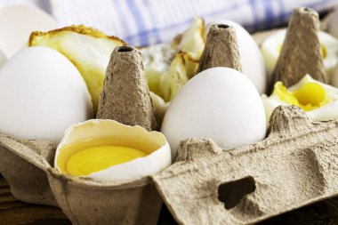 Masadaki karton bir kutunun içindeki yumurtalar bazı yumurtalar bütündür diğerleri farklı derecelerde hazırlıklıdır. Yüksek kalite fotoğraf