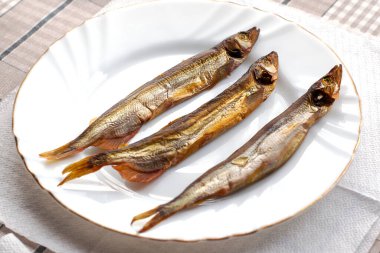 Beyaz bir tabakta tütsülenmiş üç kapelin. Yüksek kalite fotoğraf