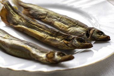 Beyaz bir tabakta tütsülenmiş üç kapelin. Yüksek kalite fotoğraf