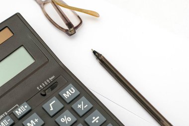 Hesap makinesi gözlüğü ve dolmakalem beyaz kağıt bir yaprak üzerinde