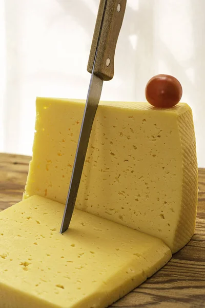 Two Pieces Cheese One Knife Stuck Other Cherry Tomato Wooden — Stock Photo, Image