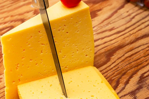 Two Pieces Cheese One Knife Stuck Other Cherry Tomato Wooden — Stock Photo, Image