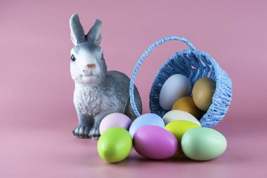 Bir tavşan ve pembe arka planda renkli Paskalya yumurtaları olan ters çevrilmiş bir sepet. Yüksek kalite fotoğraf