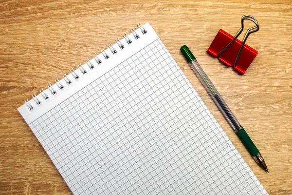 a clean open notepad for writing a fountain pen and a stationery clip on a wooden table. High quality photo