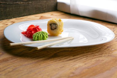 Beyaz tabakta yılan balığı wasabi zencefilli ve çubuklu fırında suşi. Yüksek kalite fotoğraf