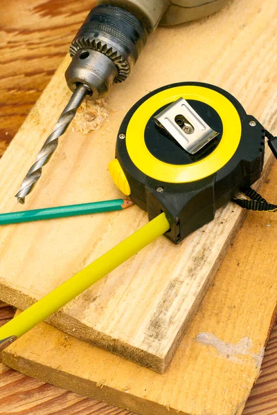 measuring tape pencil and electric drill with drill on board construction repair concept. High quality photo