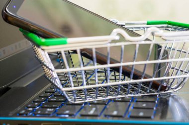 Alışveriş arabasının akıllı telefonundaki dizüstü bilgisayarda alışveriş sepetinin üstünde. Yüksek kalite fotoğraf