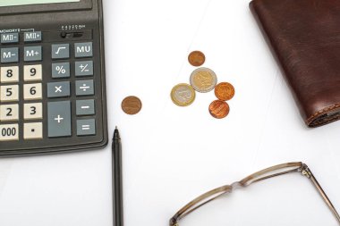 Cüzdan hesap makinesi gözlüğü dolmakalem ve masa başı bütçesi finansmanında beyaz kağıt üzerine küçük paralar. Yüksek kalite fotoğraf